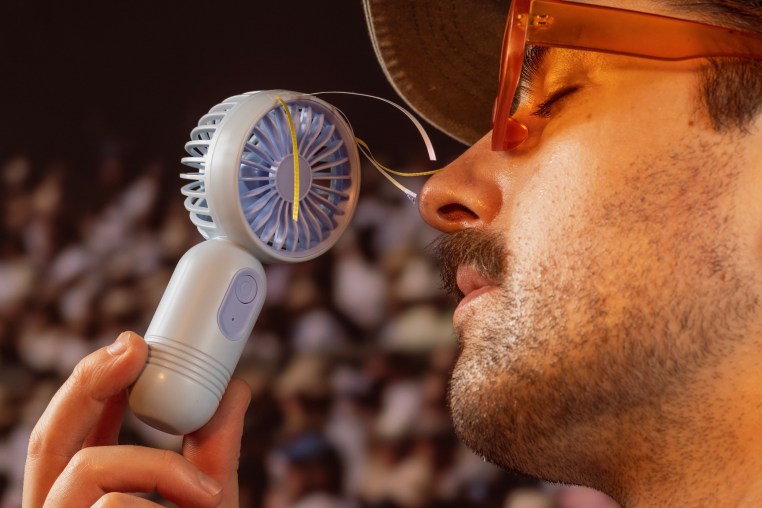 a man holding a portable fan