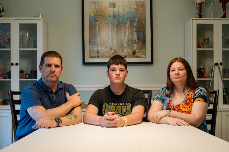 From left, Nick, Jonathan, and Misty Benz-Bushling sit at their kitchen table to pose for a photo