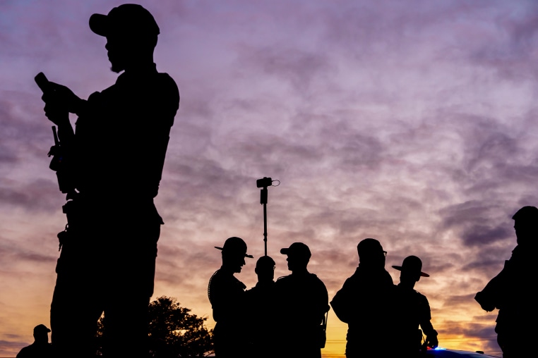 Law enforcement stand outside during a curfew outside an Immigration and Customs Enforcement (ICE) processing facility.