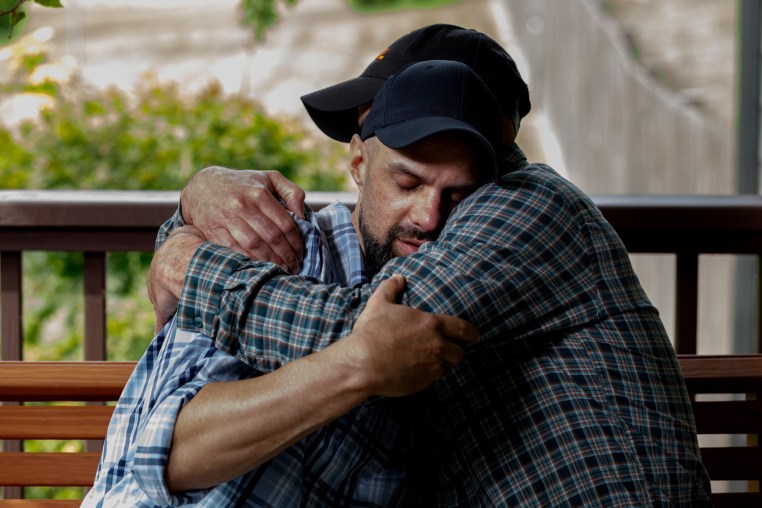 John Middleton and his twin brother, James, embrace on a porch bench