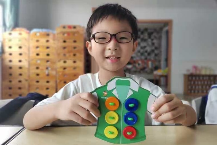 Yuanxin Zheng holding a paper craft t-shirt with buttons attached