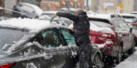 A person cleans the snow from their car.